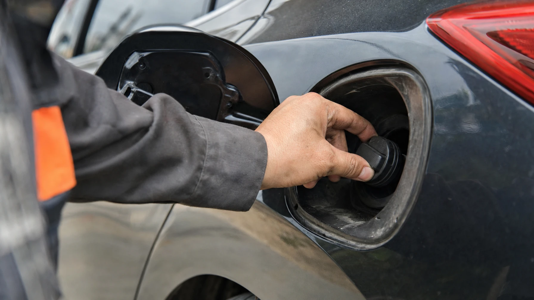 A mechanic checking a car's gas cap at the open fuel door